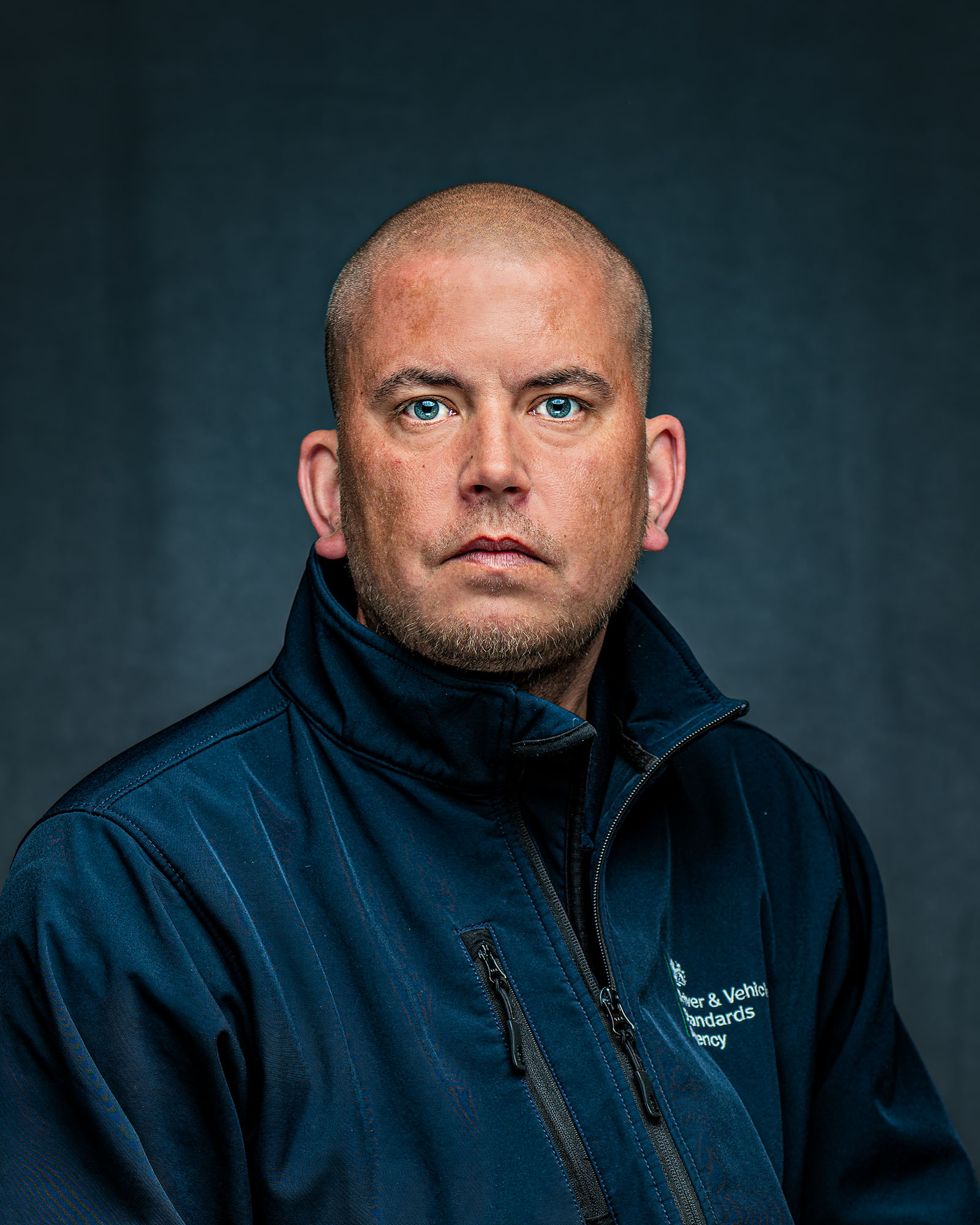 Direct corporate headshot of a man against a textured blue background