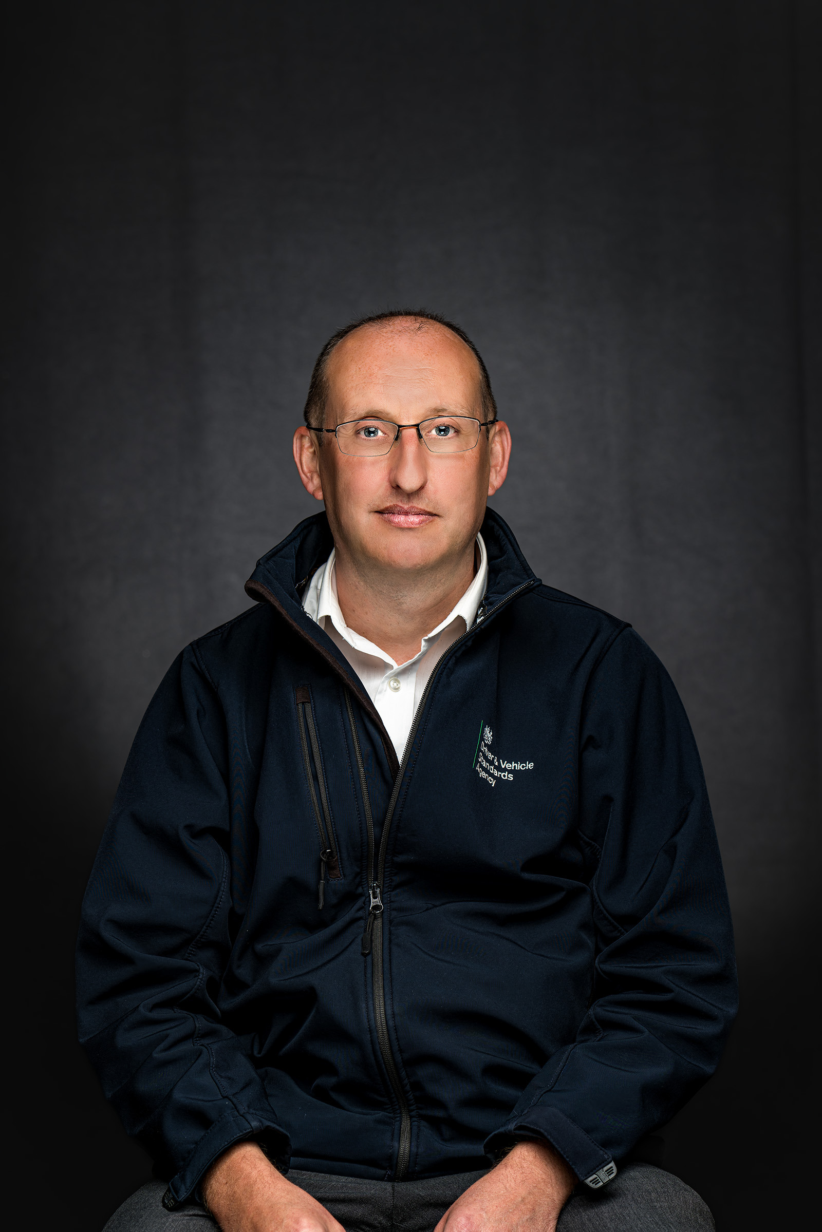 Seated staff portrait of a man wearing a dark jacket