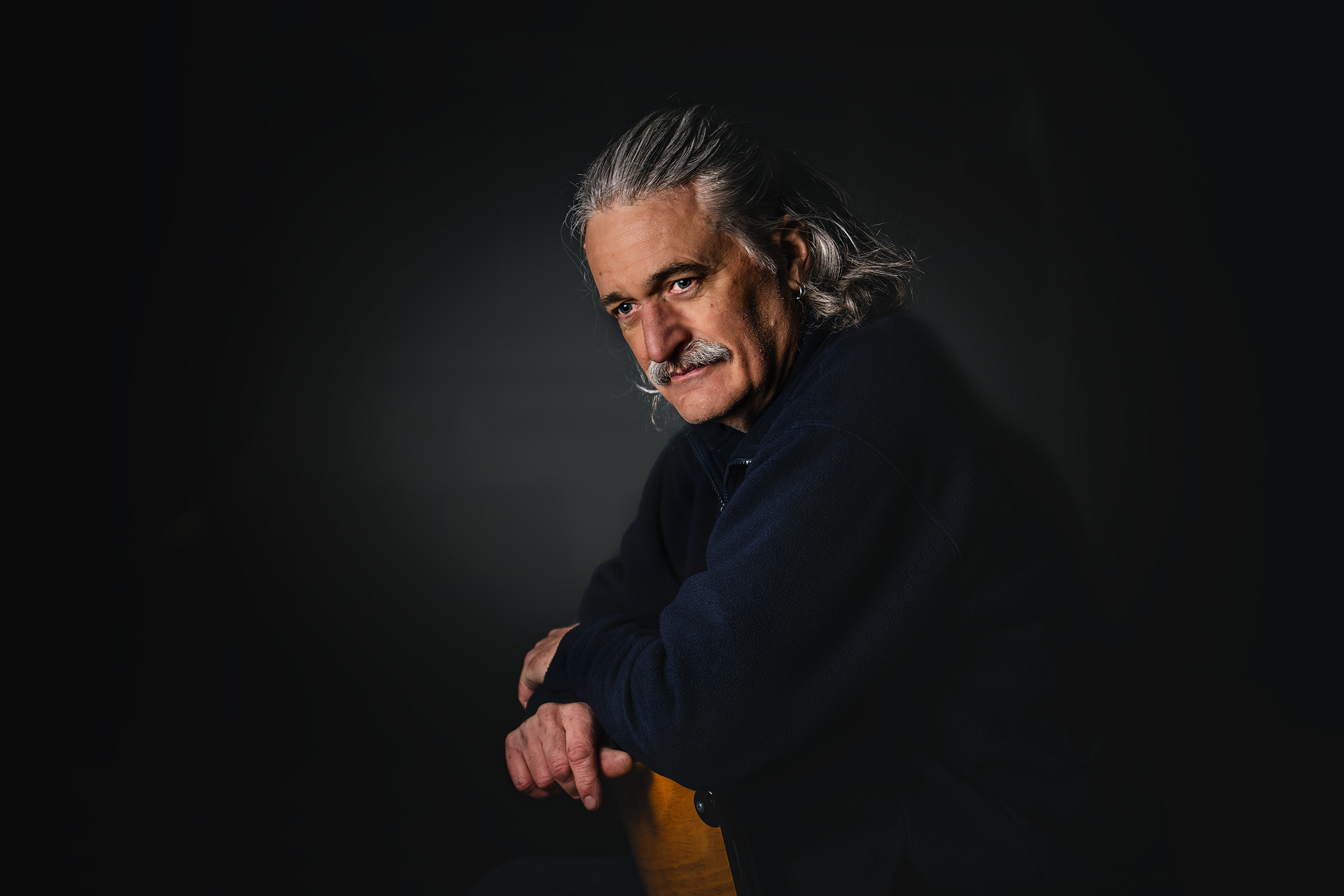 Low-key environmental portrait of a seated man