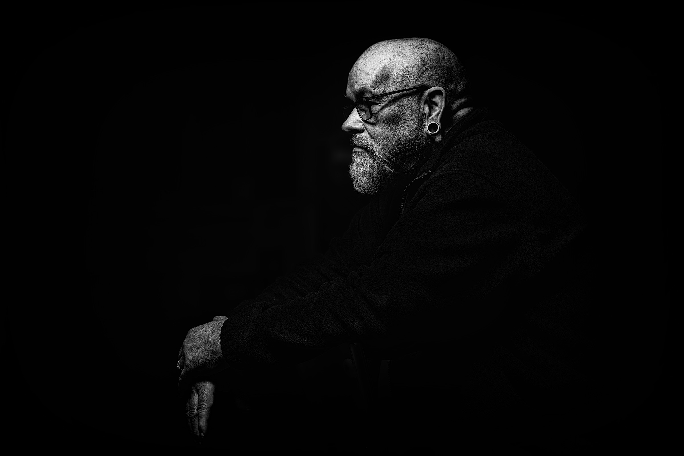 Low-key profile portrait of a seated man