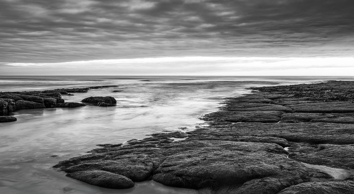 Black-and-white long-exposure study of a rocky shoreline