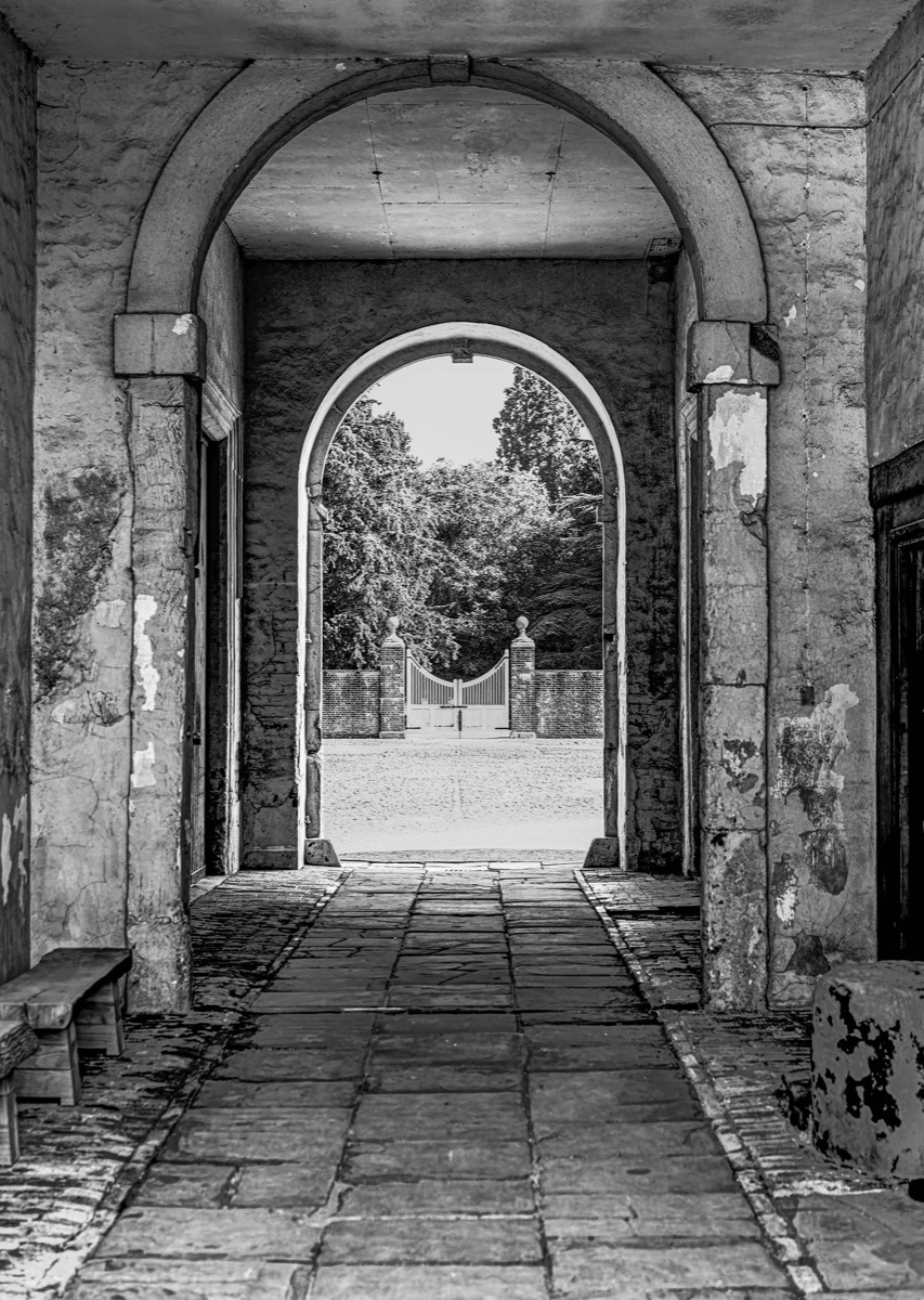 Nested stone archways leading towards a garden gate