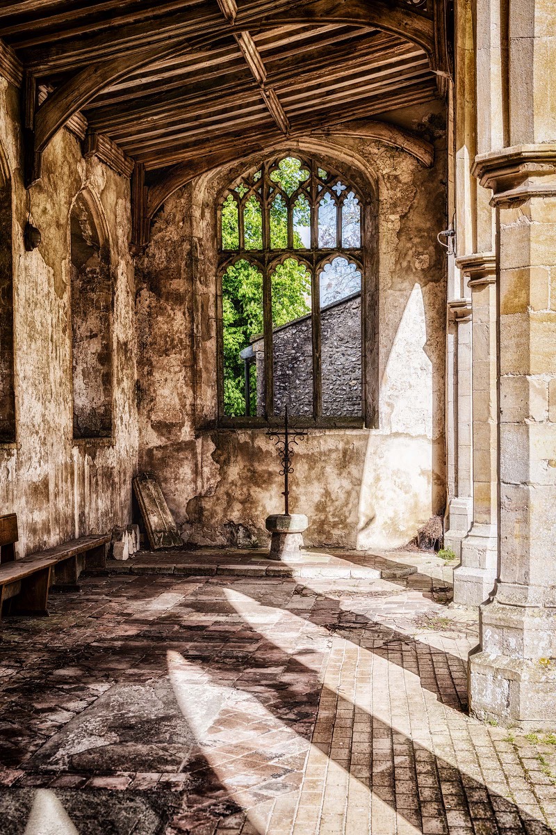 Sunlight entering a historic church aisle through a tall window