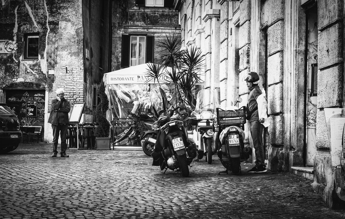 Black-and-white Rome street scene with scooters and two people